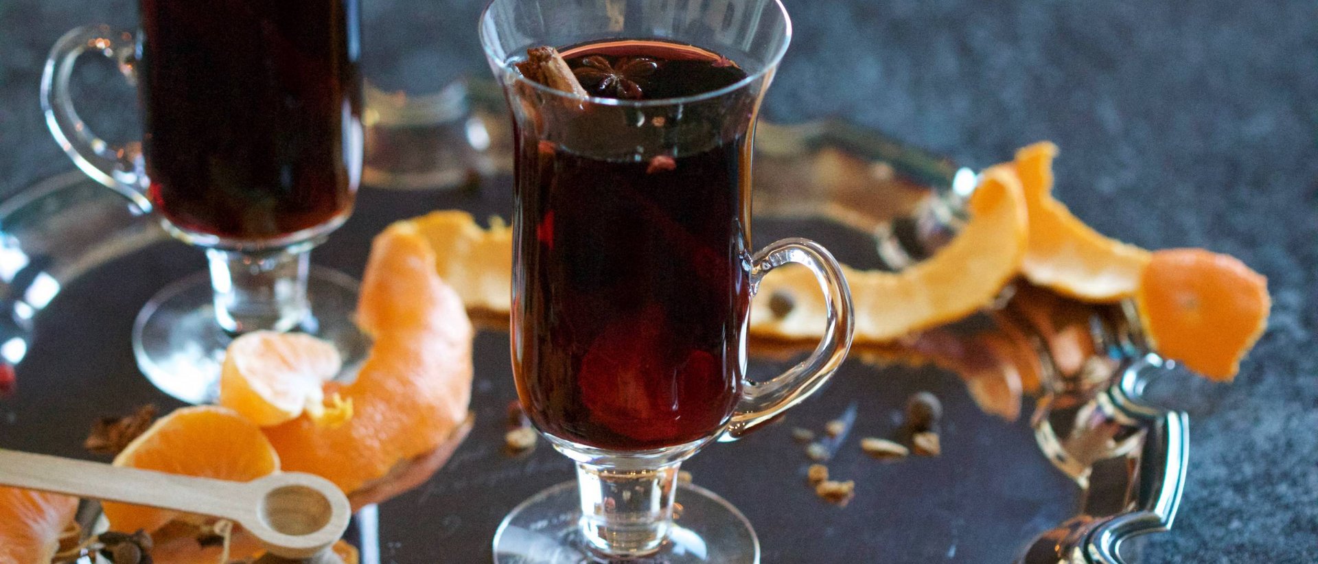 Heißte Getränke für kalte Wintertage Glas mit Glühwein auf silbernem Tablett mit Orangenschalen und Gewürzen
