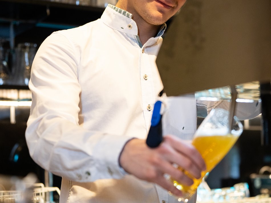 Hotel in Pertisau/Lake Achensee: join us! Bartender in white shirt pouring draft beer in a glass