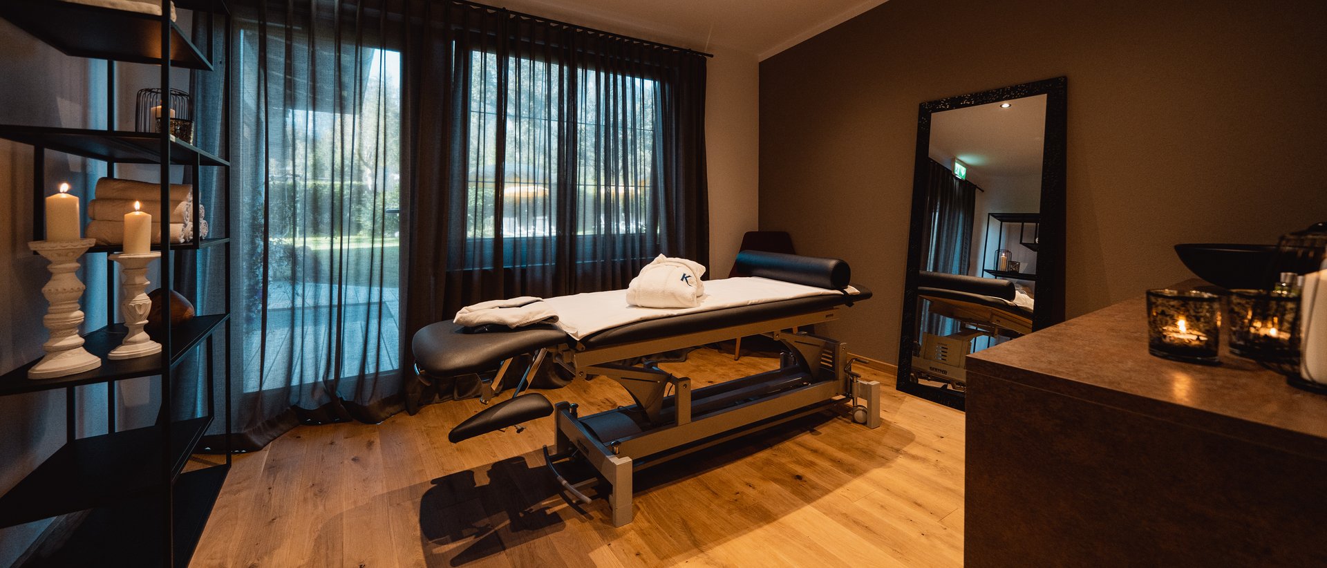 Balsam für die Haut Ruhiger Behandlungsraum mit Liege, Kerzen und Spiegel