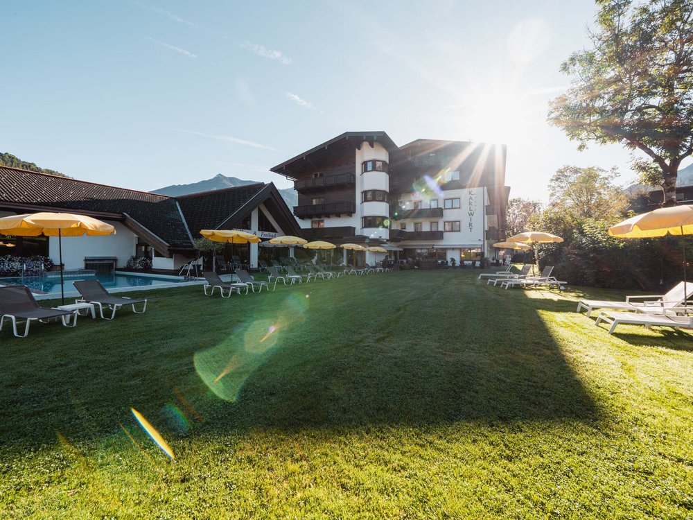 Karlwirt am Achensee: die Geschichte Hotelgarten mit Liegestühlen und Sonnenschirmen bei Sonnenlicht