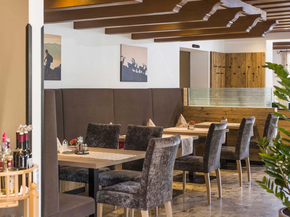 Your restaurant on Lake Achensee: the Karlwirt Cozy dining area with wooden tables, brown chairs, and decorative wall art